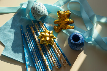 Baby showers decor. Blue and golden color straws, teddy bear, napkins, ribbons for gender reveal party, newborn baby, boy's birthday.