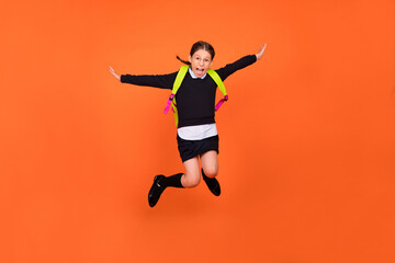 Photo of careless a-student schoolgirl jump crazy flight wear uniform backpack isolated orange color background
