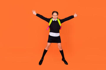 Fototapeta na wymiar Full length photo of cheerful happy schoolgirl jump up wear backpack glasses isolated on orange color background