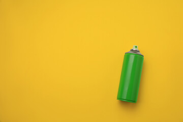 Can of green graffiti spray paint on yellow background, top view. Space for text - obrazy, fototapety, plakaty