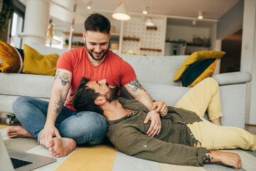 Happy gay man lying in his partner's lap and having a wonderful time with him. His partner looking at him with the love in his eyes and cuddling him.