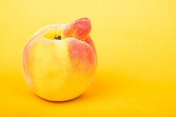 peach sexy fruit of an unusual shape with copy space on yellow background.
