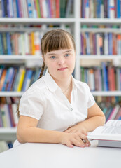 Portrait of a young girl with syndrome down at library.  Education for disabled children concept