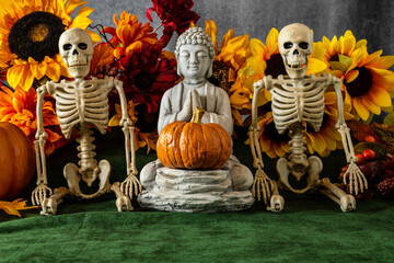 praying Buddha statue with pumpkin and skeletons with sunflower background