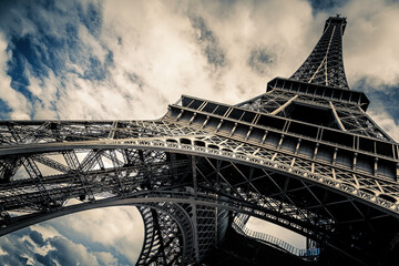Eiffel Tower with blue sky and cloud background. Low angle view looking up. Built by engineer Gustave Eiffel, and opened in 1889. Champ de Mars, Paris