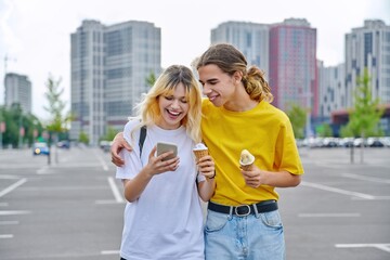 Happy laughing couple of teenagers walking hugging together in city