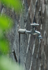 Close up of faucet with stone wall background