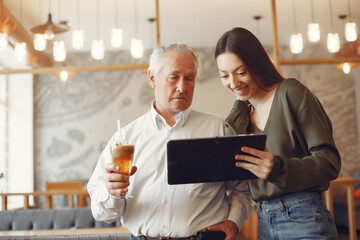 Girl teaching her grandfather how to use a tablet