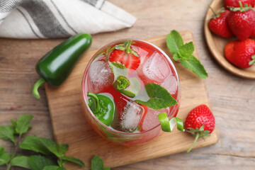 Spicy strawberry cocktail with jalapeno and mint on wooden table, flat lay