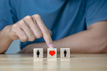 man's hand pointing to Wooden blocks with an icon of a woman and a man and love. The concept of love between spouses.