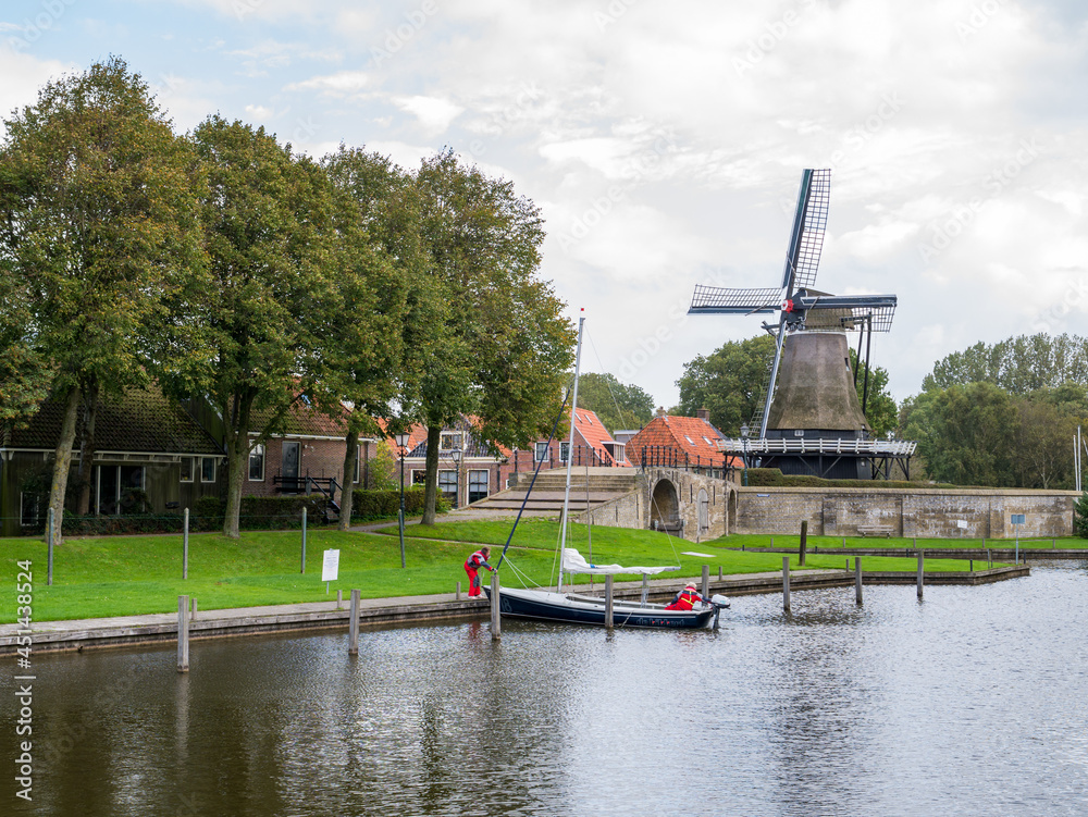 Wall mural Windmill de Kaai and canal with sailboat in city of Sloten, Sleat, Friesland, Netherlands