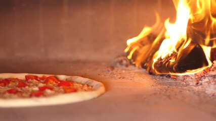Baking pizza in the oven in pizzeria near open fire of burning wood