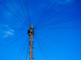Single telegraph pole with many cables in Leeds, looking up toward blue sky.