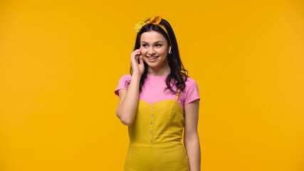 Smiling woman listening music in earphones isolated on yellow.