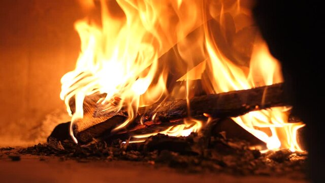 Burning wood fire in oven  preparing to cook pizza in a pizzeria restaurant closeup slow motion