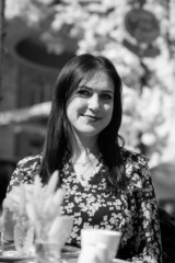Smiling stylish woman in black shirt sitting at the table drinking coffee in the terrace of restaurant.