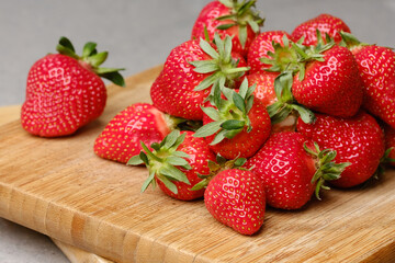 Pile of strawberries on a wooden kitchen board. 