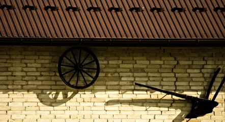 Stare koło i pług na ścianie starej stodoły. An old wheel and a plow on the wall of an old barn.