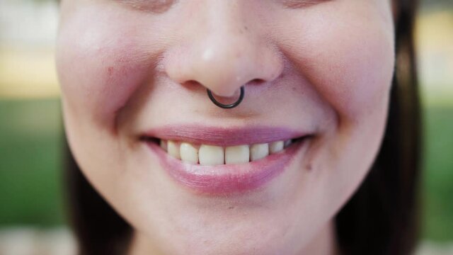 Close-up face of asian punk girl wearing piercings nose ring. Beauty individuality concept.