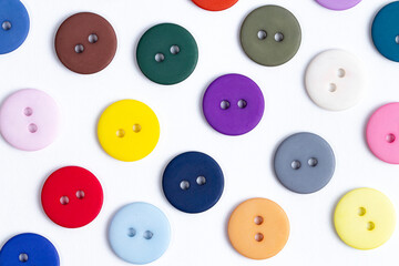 A pattern of colored buttons close-up on a white background, sewing supplies.
