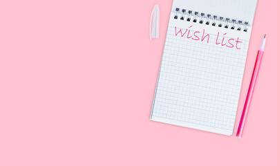 Notepad with the inscription Wishlist on a pink background top view, banner or flyer mockup, flat lay.