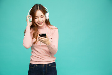 Asian woman listening favourite music or video clips with headphones isolated on green background