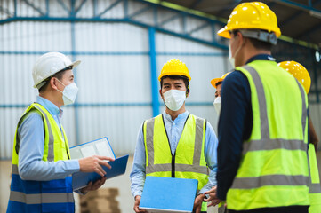 The factory employee consists of engineers, foreman, technicians, and related department staff. Wear a mask, hard hat, and vest. meeting before starting work inside the warehouse. Teamwork concept.