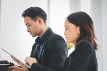 Businesswoman discussing charts and graphs showing on tablet screen with friend with smiling faces in the meeting room. Brainstorming and teamwork concept.