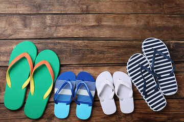 Many different flip flops on wooden background, flat lay. Space for text