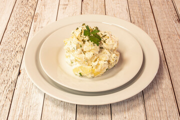 Great Spanish tapa of cooked potatoes with aioli sauce of mayonnaise, garlic and parsley on a white plate served in a tapas restaurant