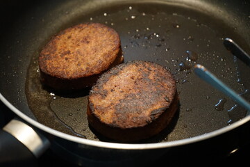 vegan plant-based burger patty being fried in pan with coconut oil