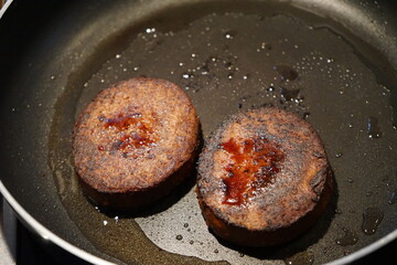 vegan plant-based burger patty being fried in pan with coconut oil