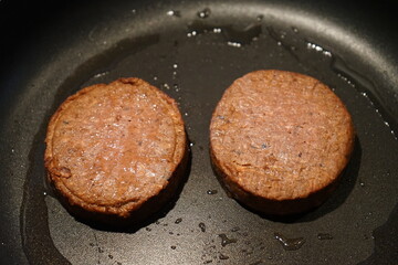 vegan plant-based burger patty being fried in pan with coconut oil