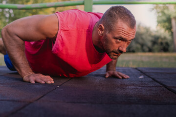 Fototapeta premium handsome muscular man wearing red shirt doing push ups
