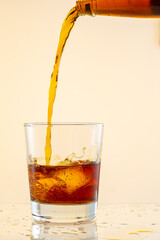 splash from falling ice glass with whiskey on white background