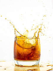 splash from falling ice glass with whiskey on white background