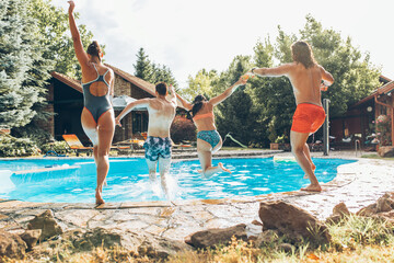 A young group of people jumping into the swimming pool.Having fun and refreshing on a hot summer...