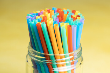 Pile of colorful plastic straws in a glass jar