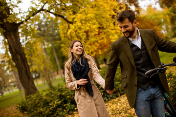 Young couple in the autumn park with electrical bicycle
