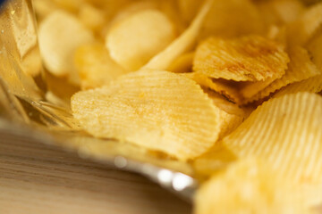 crispy potato chips in snack bag on wood table