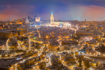 Fototapeta na wymiar Aerial night view of the skyline of the old snowy European city with the ancient cathedral in a snowy night, Filomena, Toledo, Spain.