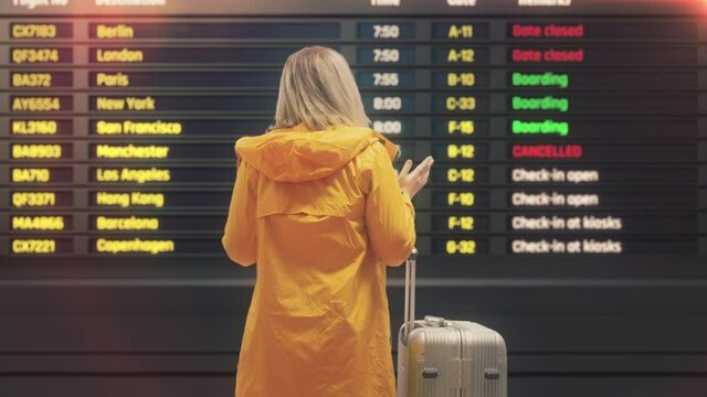 Young woman with suitcase upset that her flight was canceled, waiting in airport