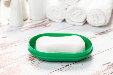 new soap on a green plastic soap dish, on a white wooden background.