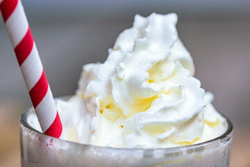 A glass of coffee drink. A cup of cappuccino with whipped cream and a cocktail tube.