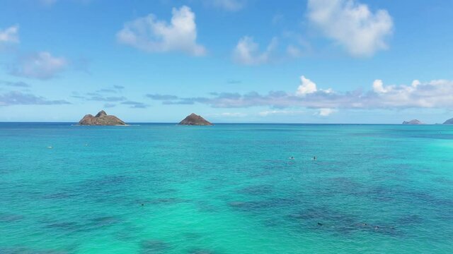 Aerial view of the twin Mokulua Islands off the coast of Lanikai beach in Oahu, Hawaii, with turquoise water and visible coral reefs in the foreground.