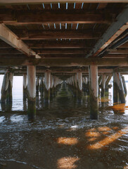 Wooden pier columns standing in the sea. Baltic Sea pier in Poland. Waterfront under the pier made of wood.