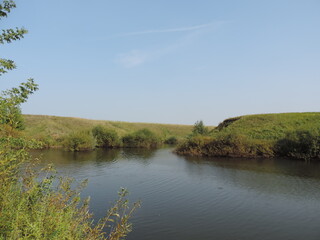 Fototapeta na wymiar A pond in the steppe against the blue sky.