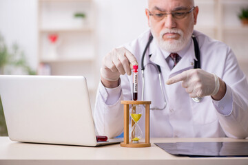 Old male doctor in time management concept