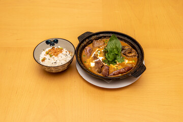 Super red pork curry with mushrooms and sour cream garnished with white rice and coriander and basil leaves