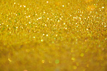 The blurred texture of the golden shine. Background with gold glitter or yellow sequins. Seamless texture with yellow gold sequins. Flickering background. High quality photo